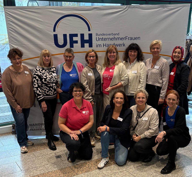 Frauen, Mitglieder der Arbeitskreise UFH Schleswig-Holstein, vor einer UFH-Plakatwand